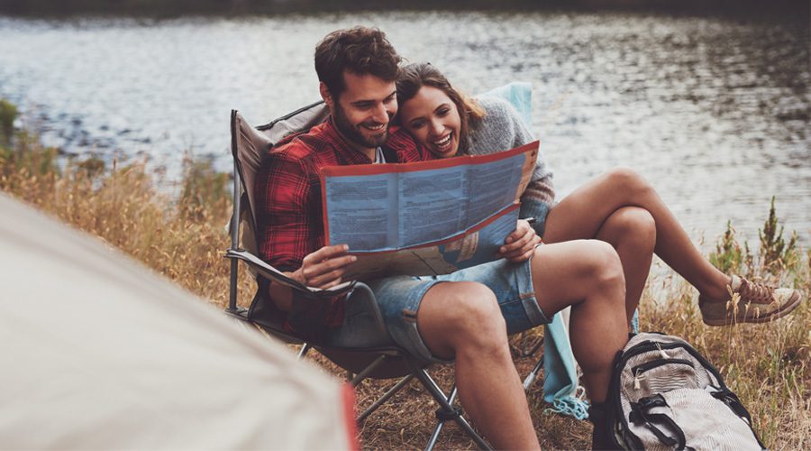 Couple sitting in a chair, and smiling while looking at a map