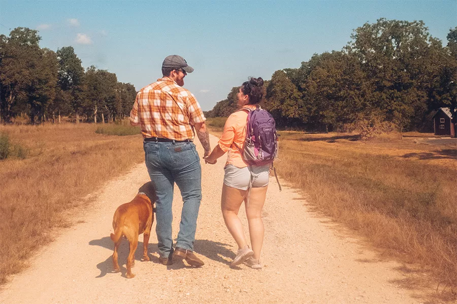 couple walking with dog on trail jpg